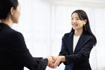 Young Japanese businesswoman in a suit shaking hands with a client and smiling © hidez