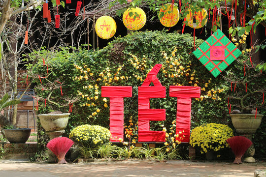 Vietnamese Lunar New Year photo zone with big red TET letters and yellow hats decoration with calligraphy text meaning Peace Health and Prosperity