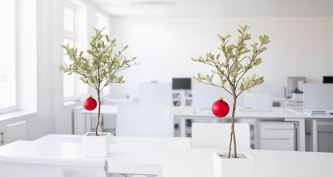 A biophilic office design incorporates a living pistachio-green potted tree, lightly decorated with delicate red glass drops.
