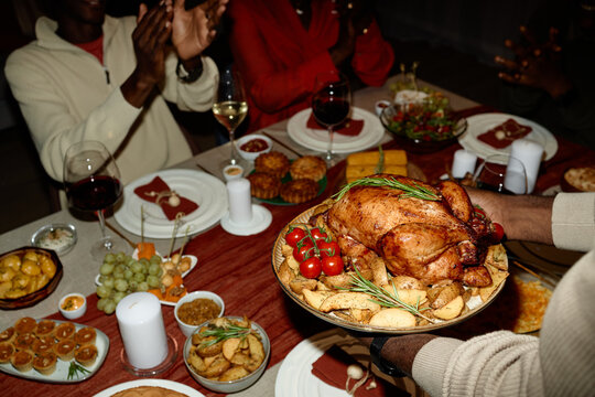 African American young adults celebrating Thanksgiving dinner at home while serving roasted turkey. Image ideal for holiday marketing campaigns and family lifestyle promotions