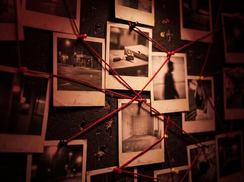 Investigation wall with connected photos and red string for detective work