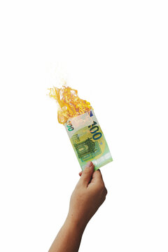  Hand holding several 100 Euro bill  on fire, isolated on free white background.