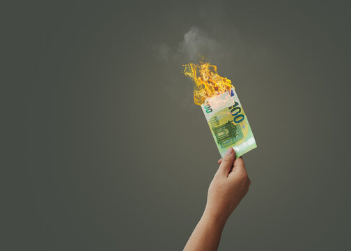  Hand holding several 100 Euro bill  on fire, isolated on free background.