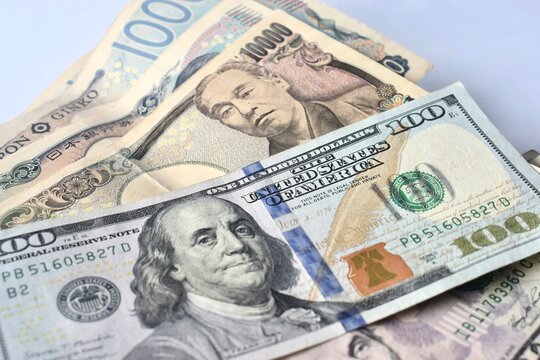 Overhead view of mixed global currencies featuring US 100 dollar bills and Japanese 10,000 yen banknotes, symbolizing international forex trading and global finance.