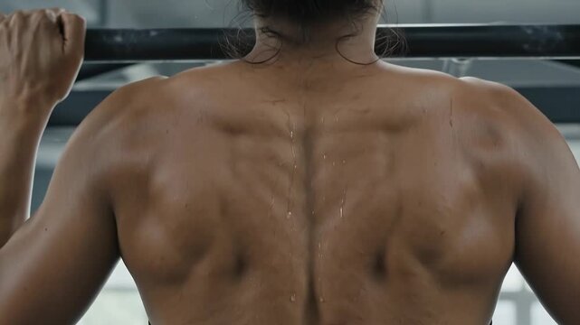 Close Up Rear View of Strong Woman Doing Pull Ups on Bar with Muscular Back in Gym