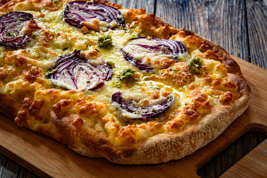 Pinsa bianca white pizza with red onion and oregano on wooden table
