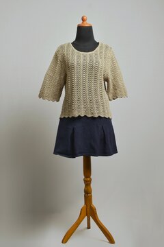 Cute milk brown crocheted blouse with navy mini skirt on a dress form