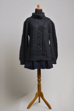 Black cable knit turtleneck sweater with mini skirt displayed on a dress form