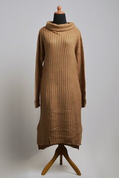 Caramel small cable knit sweater dress with long sleeves and turtleneck on a mannequin display
