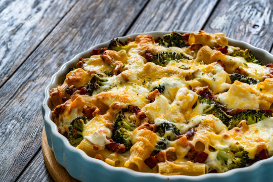 Pasta casserole with broccoli and smoked bacon on wooden table
