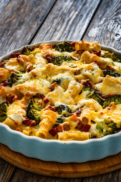 Pasta casserole with broccoli and smoked bacon on wooden table
