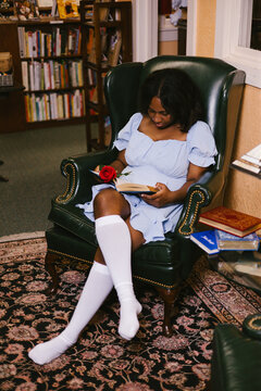 Young black woman reading in a cozy library chair