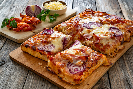 Pizza with bacon, mozzarella cheese and red onion on wooden table
