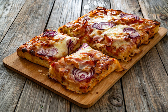 Pizza with bacon, mozzarella cheese and red onion on wooden table

