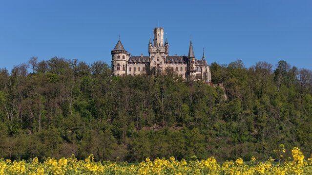 Nordstemmen, Lower Saxony, Germany &ndash; April 21, 2026 - Marienburg Castle rises above a wooded hillside and a bright yellow rapeseed field during spring. 