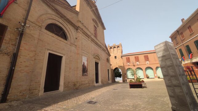 Scorcio di Piazza Beato Amato a Saludecio, con la facciata in mattoni della settecentesca Chiesa di San Biagio e la storica torre civica sullo sfondo