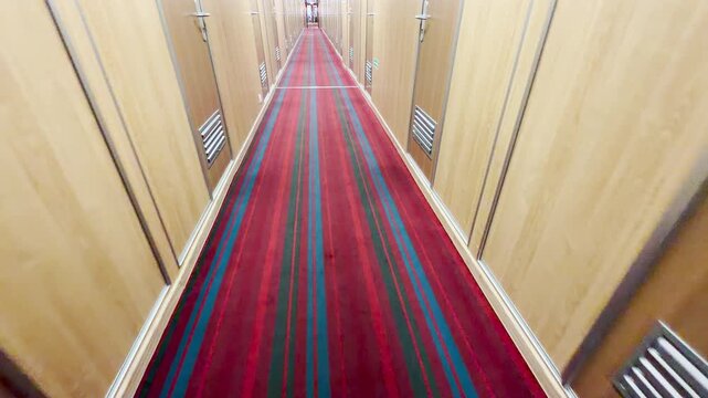 A cruise ship corridor stretches along cabins on Lake Ladoga. The red striped carpet leads through the empty hallway. This quiet indoor view feels calm and cozy.