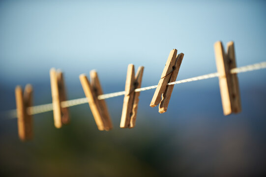Wooden Clothespins Hanging on Clothesline Against Blue Sky Outdoor Background