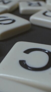 Macro shot of white letter tile on dark table, word game board game scrabble footage