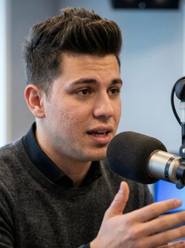 Close up portrait of expressive young male podcaster talking near pop filter microphone