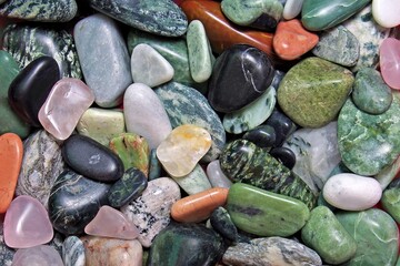 Full frame background texture of colorful polished gemstones, smooth river pebbles, and healing crystals. © dovis
