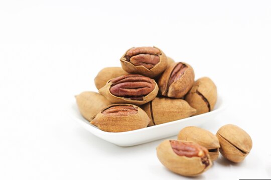 Group of whole and cracked pecan nuts with kernels, isolated on a clean white background.