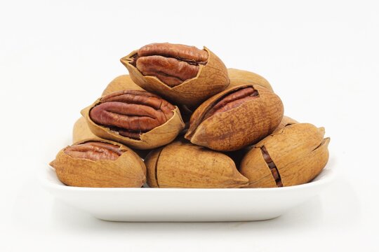Group of whole and cracked pecan nuts with kernels, isolated on a clean white background.