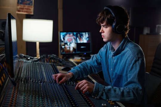 Sound engineer carefully calibrating sound levels in dimly lit studio