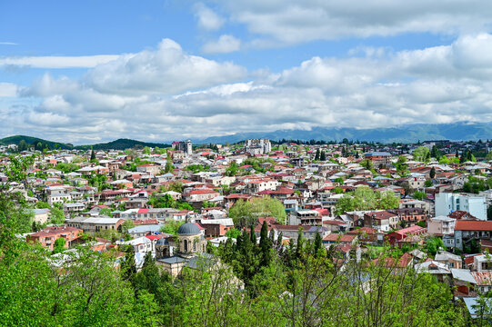 Panoramic view of the Old Town of Kutaisi with its traditional houses, church towers, and green hills under a partly cloudy sky, Imereti region, Georgia