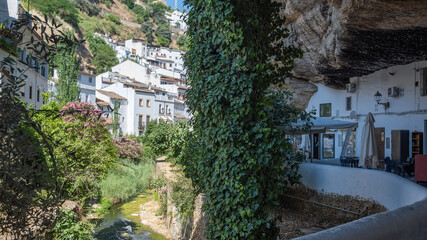 Casas cueva debajo de cornisa de roca y río Trejo en la idílica villa de Setenil de las Bodegas, pueblos blancos de España © David Andres