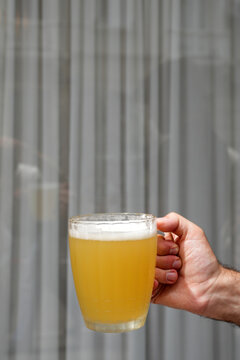 Hand holding frosty glass mug of unfiltered beer POV shot