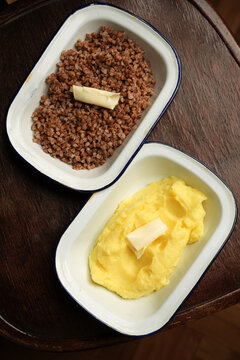 Buckwheat porridge and mashed potatoes with butter in enamel dishes flat lay
