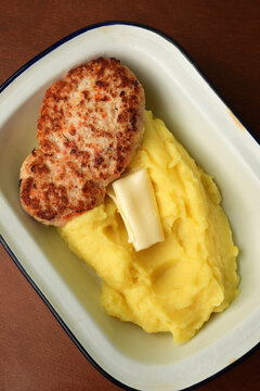 Fried chicken cutlet with mashed potatoes and butter in enamel dish close up