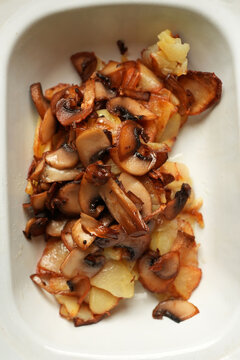 Pan-fried potatoes with wild mushrooms in enamel dish close up