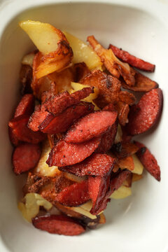 Pan-fried potatoes with smoked sausages in enamel dish flat lay