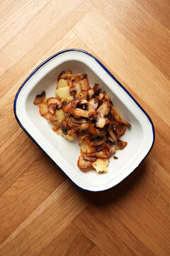 Pan-fried potatoes with wild mushrooms in enamel dish close up