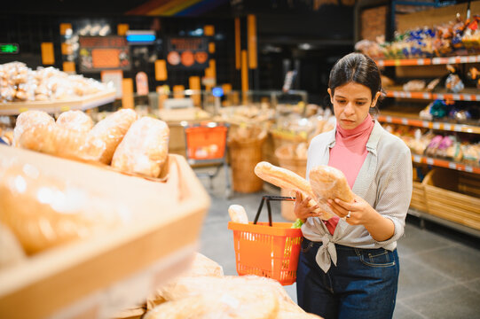 Indian woman choosing bread in supermarket bakery section