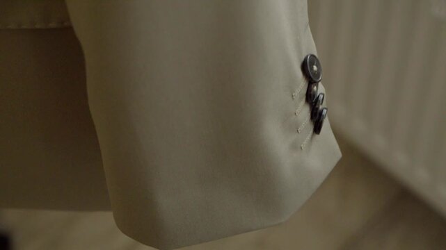 Close-up detail of an elegant cufflink on the groom's formal shirt during wedding preparations.