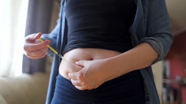 Woman making hormone injection into belly at home for ivf fertility treatment and ovulation stimulation. Concept of reproductive medicine, hormone therapy, and subcutaneous injection.