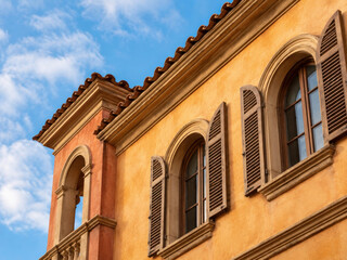 Fototapeta premium Tuscan Style Villa Facade, Yellow , Arched Windows with Wooden Shutters, Orange Plaster Wall, Clay Roof Tiles, Mediterranean Architecture