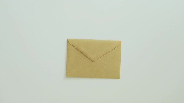 A woman's hand places a sealed kraft envelope on a white surface