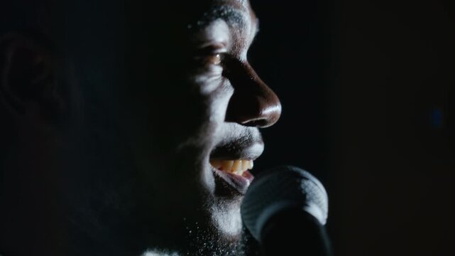 African American young adult man singing and speaking into microphone during student theater performance. Footage suited for arts education, music academy promotion and live stage advertising