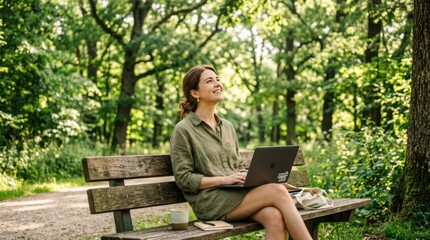 Fototapeta premium Woman working on laptop in a serene forest park enjoying nature.