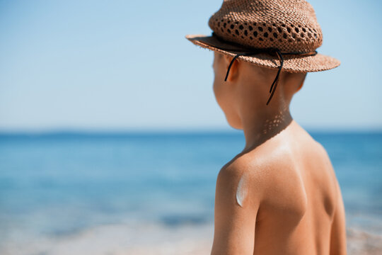 Child by the sea at summer vacation with sun protectin sunscreen and hat