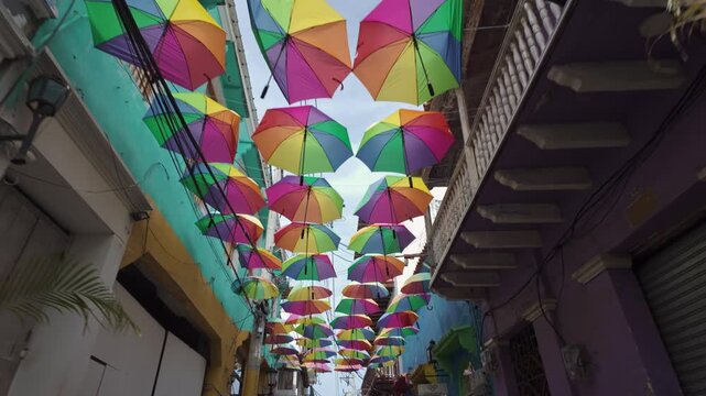 Colorful umbrellas and international flags hanging over a narrow street in Getsemani, Cartagena, Colombia, vibrant travel destination concept