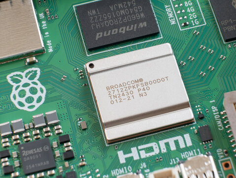 Macro shot focusing on Broadcom processor and Winbond memory chip on green Raspberry Pi 5 printed circuit board