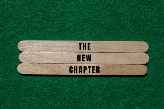 Wooden sticks arranging the words the new chapter on a vibrant green felt background, representing fresh starts and goals