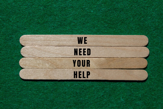 Wooden craft sticks displaying the words we need your help, conveying a strong message of support, charity, and assistance