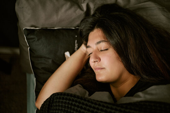 Young woman sleeping peacefully in bed, resting head on pillow. Ideal visual asset for healthcare campaigns, wellness branding, sleep hygiene and insomnia treatments