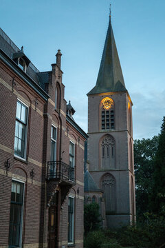 Old church tower seen at dusk near brick building in a quiet village setting